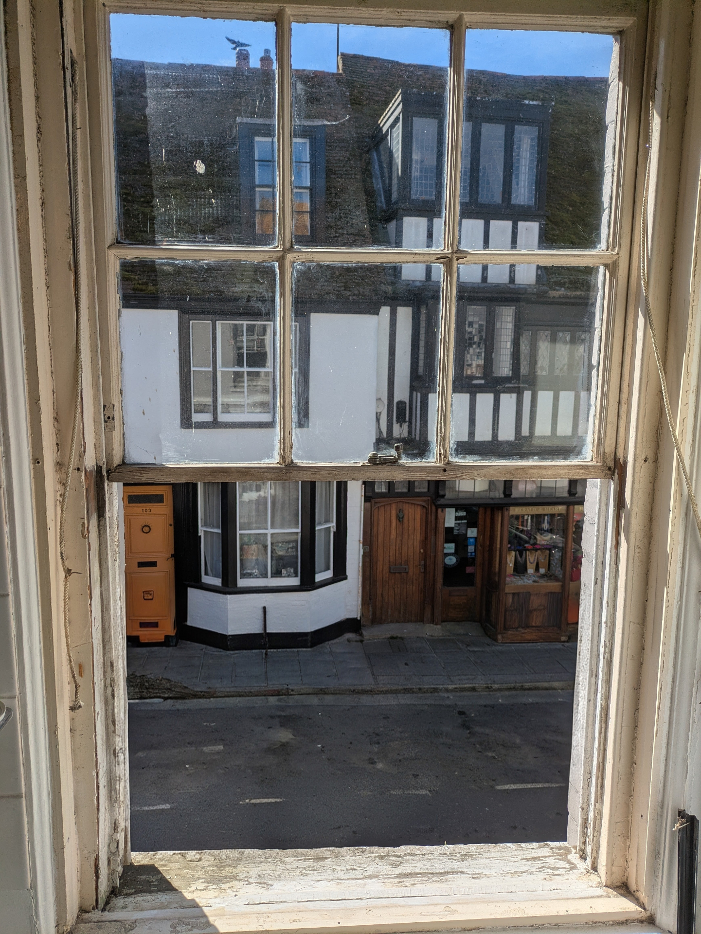 Sash window restoration with view of historic timber-framed buildings